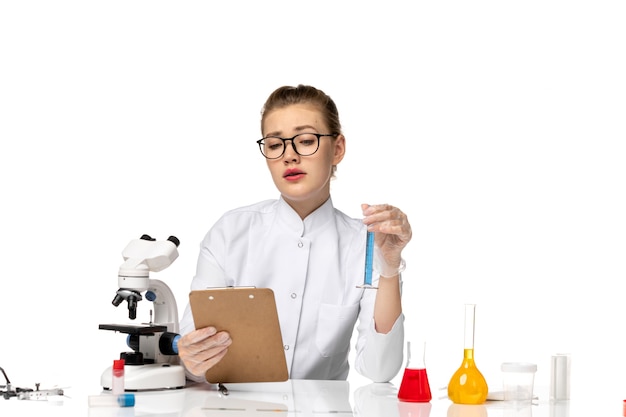 Free photo front view female doctor in white medical suit working with solutions on light white space