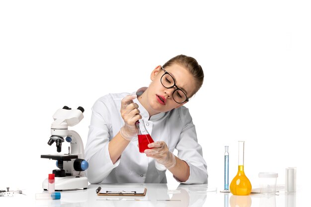 Front view female doctor in white medical suit working with solutions on the white space