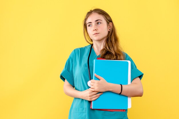 Front view female doctor with analyzes on light-yellow background medic hospital health