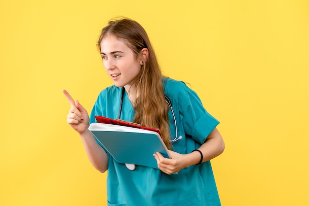 Front view female doctor with analyzes on yellow background medic hospital health virus