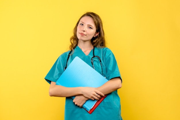 Front view of female doctor with analyzes on a yellow wall