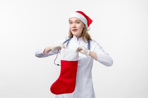 Front view of female doctor with big holiday sock on white wall