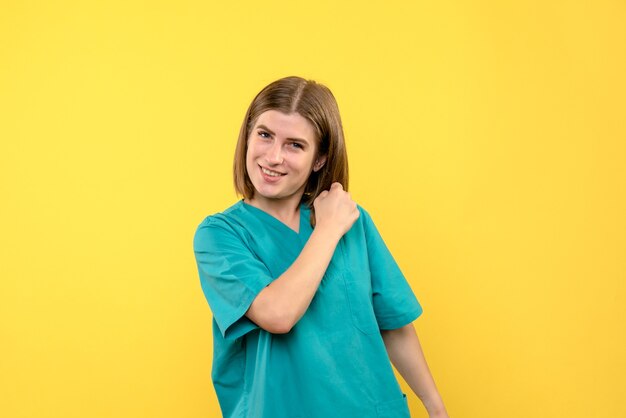 Front view of female doctor with excited face on a yellow wall