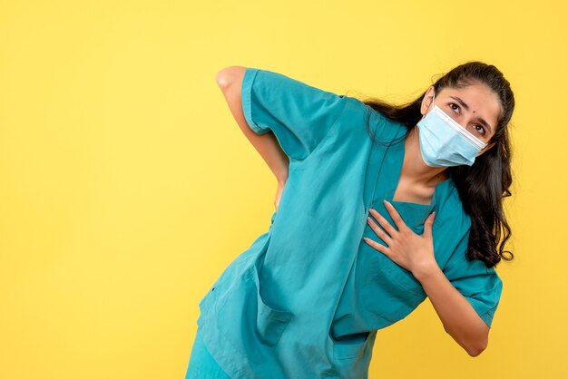 Front view female doctor with mask holding her back putting hand