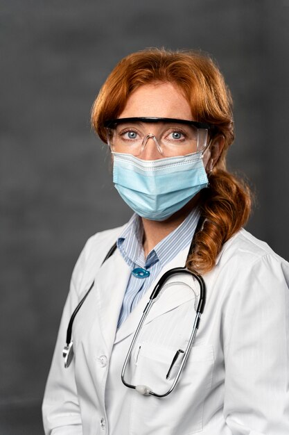 Front view of female doctor with medical mask, stethoscope and safety glasses