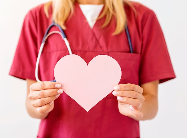 Front view of female doctor with stethoscope holding paper heart