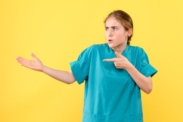 Front view female doctor on yellow background medic health hospital virus emotion