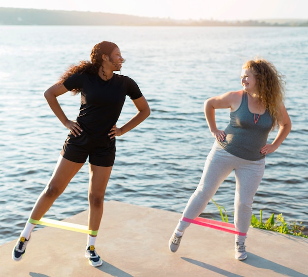 Free photo front view of female friends working out by the lake