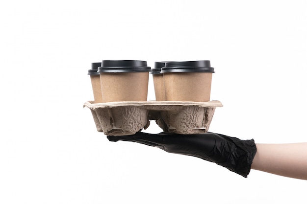 A front view female hand in black gloves holding cups with coffee on white job