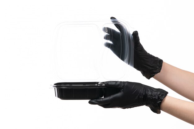 A front view female hands in black gloves holding bowl with food on white