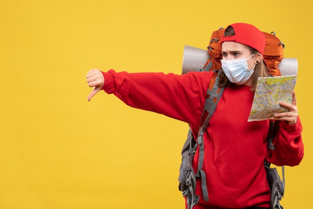 Front view female hiker with backpack and mask holding map giving thumb down