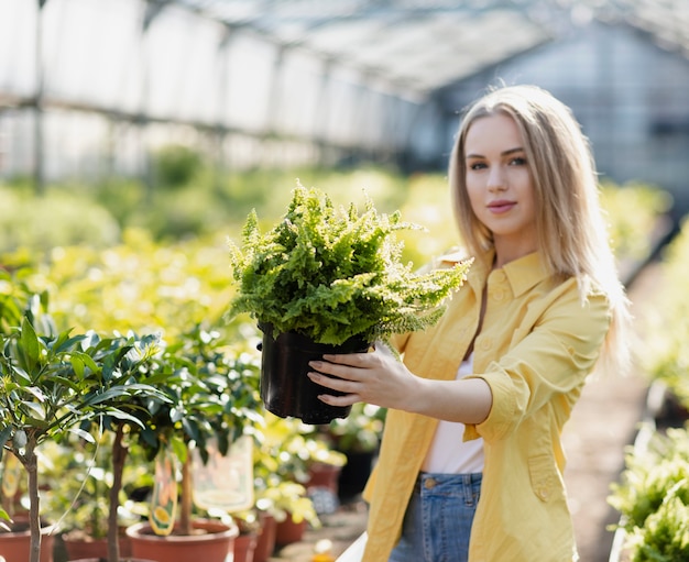 Free photo front view female looking at pot plant