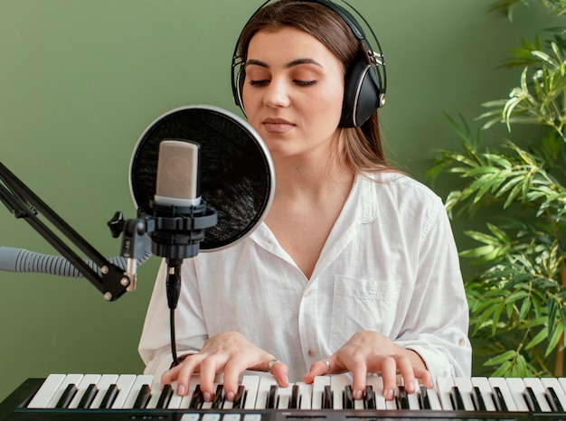 Front view of female musician singing and playing piano keyboard