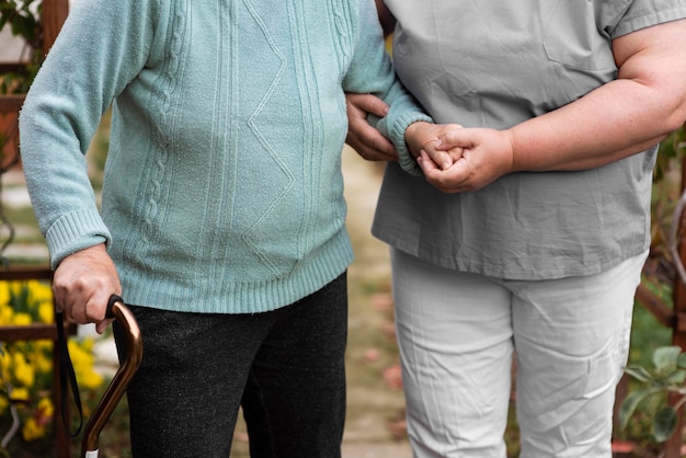 Free Photo front view of female nurse helping senior woman walk