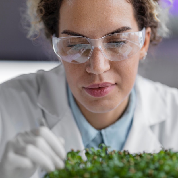 Free photo front view of female researcher in the laboratory with safety glasses and plant