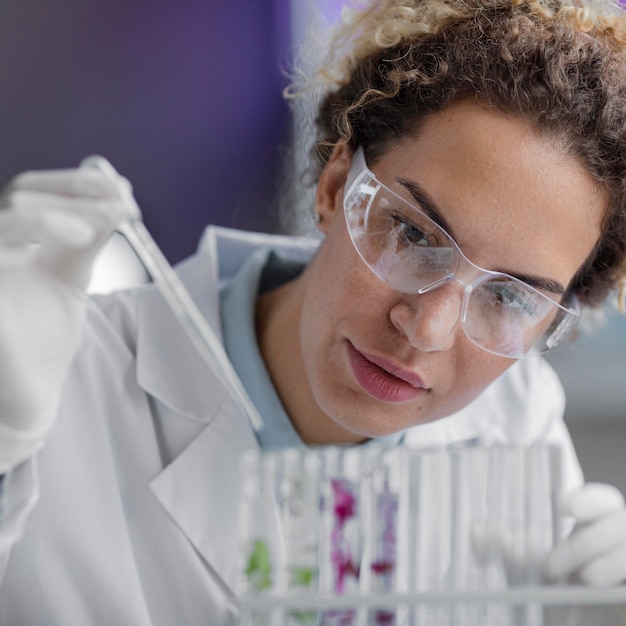 Free photo front view of female researcher in the laboratory with safety glasses and test tubes