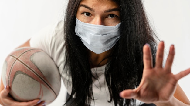 Front view of female rugby player with medical mask and ball