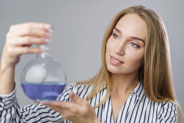 Free photo front view of female scientist holding and looking at test tube