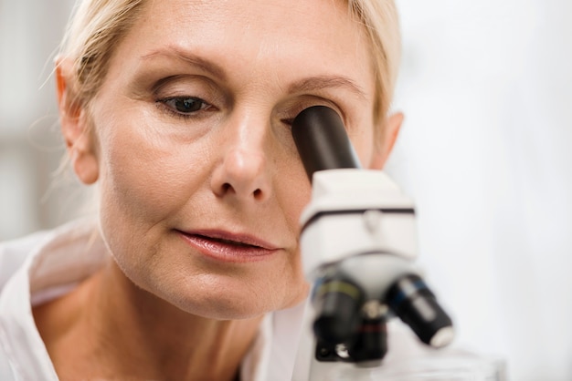 Front view of female scientist in the lab looking through microscope