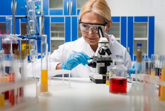 Free photo front view of female scientist working with microscope in the lab