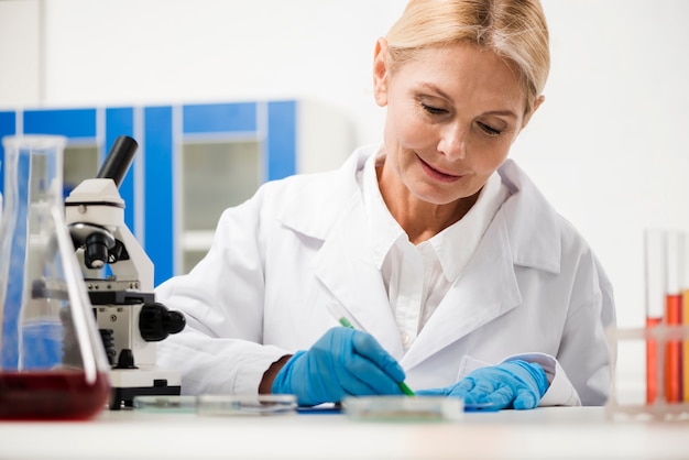 Free photo front view of female scientist writing something down in the laboratory