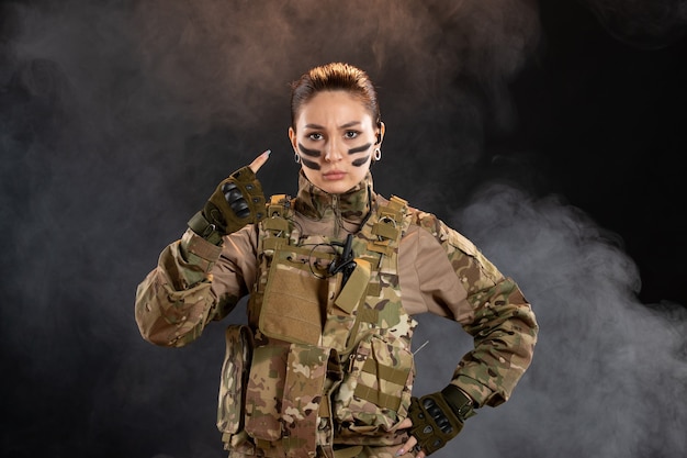 Front view of female soldier in camouflage black smoky wall