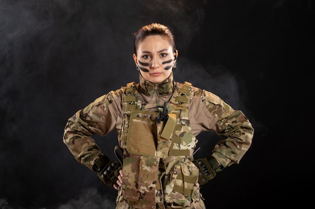 Free photo front view of female soldier in camouflage on dark wall