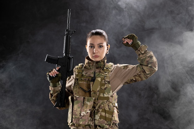 Front view of female soldier in uniform with rifle on black wall