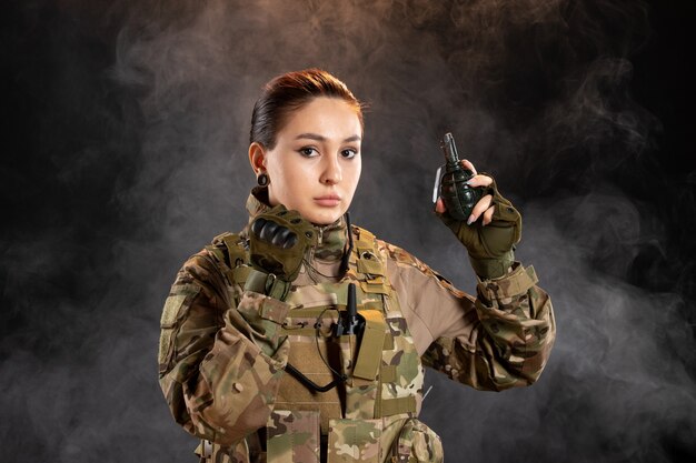 Front view of female soldier with grenade in uniform black wall