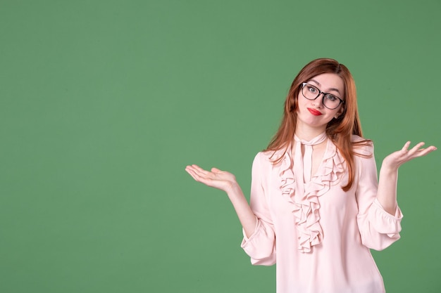 Front view female teacher in pink blouse posing on green