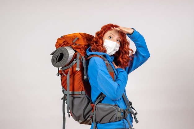 Free photo front view female tourist going in mountain trip in mask with backpack