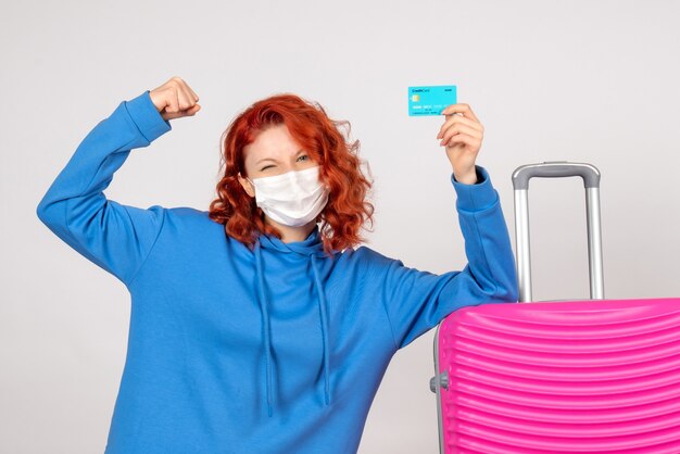 Front view female tourist holding bank card in mask