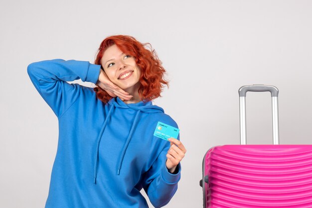 Front view female tourist holding bank card and smiling