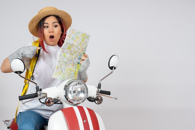 Front view female tourist sitting on motorcycle with map white wall