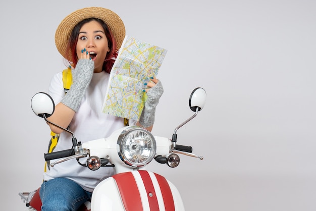 Front view female tourist sitting on motorcycle with map white wall