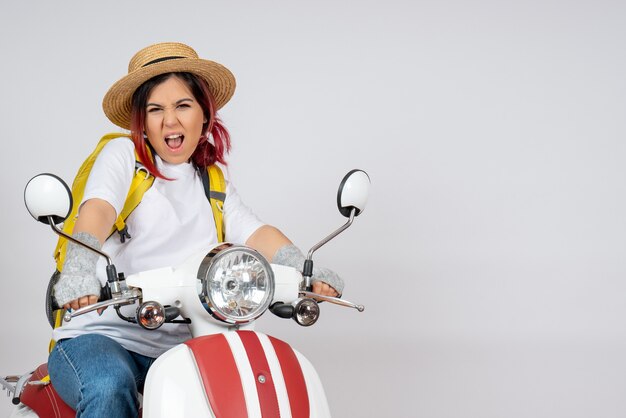 Front view female tourist sitting and posing on motorcycle on white wall