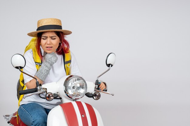 Front view female tourist sitting and posing on motorcycle on white wall