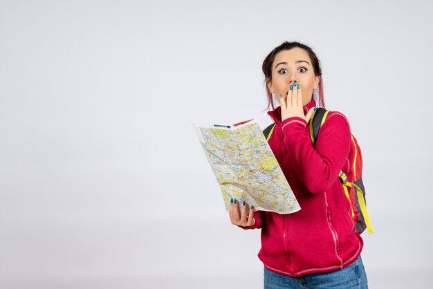 Front view female tourist with map looking for direction on white wall