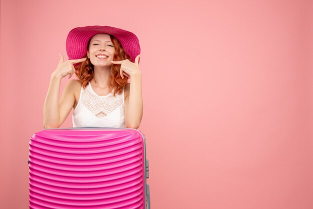 Front view of female tourist with pink bag on pink wall