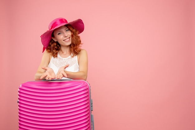 Front view of female tourist with pink bag on pink wall