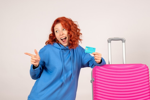 Front view of female tourist with pink bag on white wall