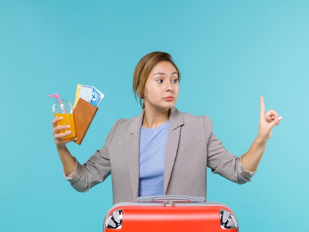 Free photo front view female in vacation holding fresh drink and tickets on blue background sea trip vacation voyage travelling journey