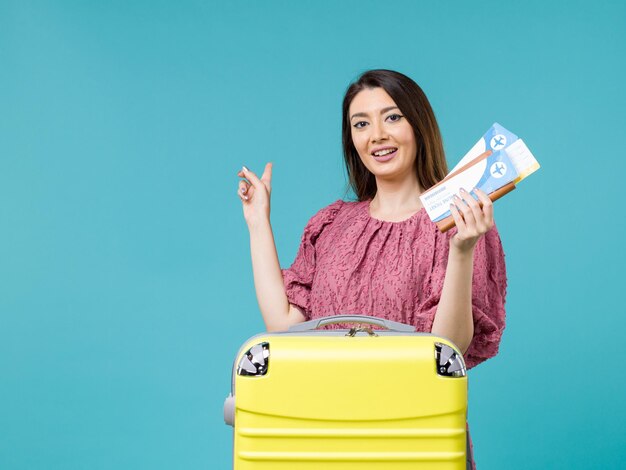 Front view female in vacation holding her tickets on light blue background journey summer trip woman sea vacation