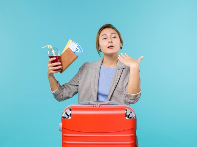 Front view female in vacation holding juice and tickets on blue desk voyage plane vacation travel trip sea