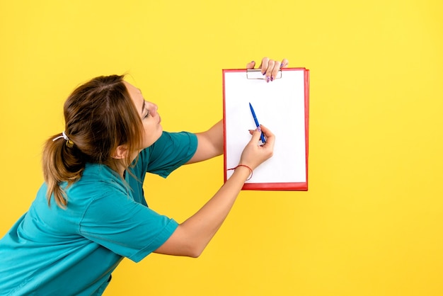 Free Photo front view of female veterinarian holding analyzes on a yellow wall