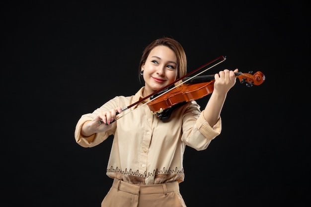 Free photo front view female violinist playing on violin with smile on her face on dark wall music concert instrument play melody emotion woman