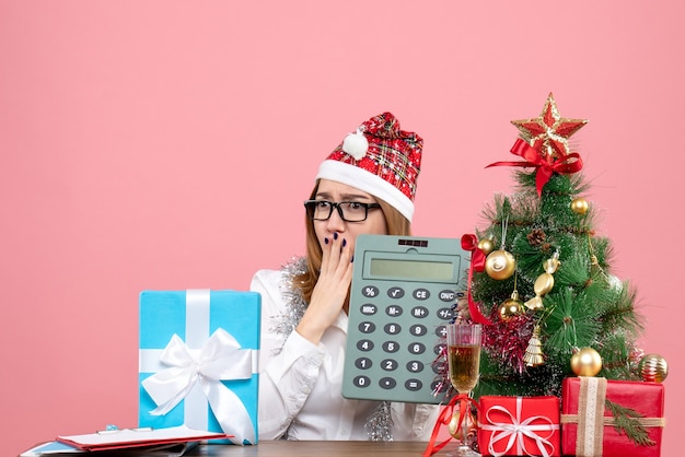 Free photo front view of female worker holding calculator around presents on pink