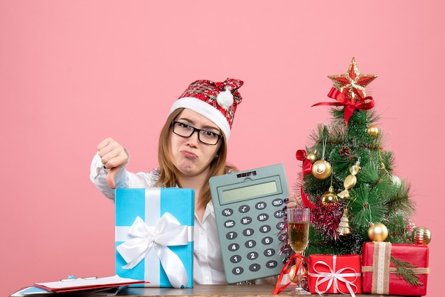 Free photo front view of female worker holding calculator around presents on pink