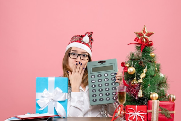 Free photo front view of female worker holding calculator around presents on pink