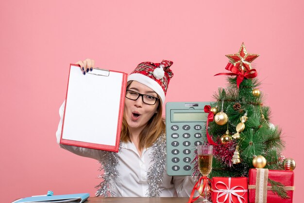 Front view of female worker holding calculator and file note on pink